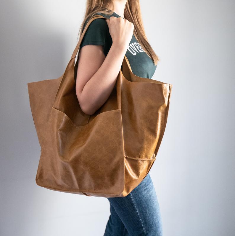 A tan leather tote bag with large capacity soft slouchy shoulder design and sturdy handles.