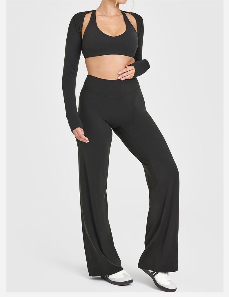 Black long-sleeved crop top with cut-out shoulders paired with high-waisted slimming yoga pants in black stretch fabric for a straight leg fit.