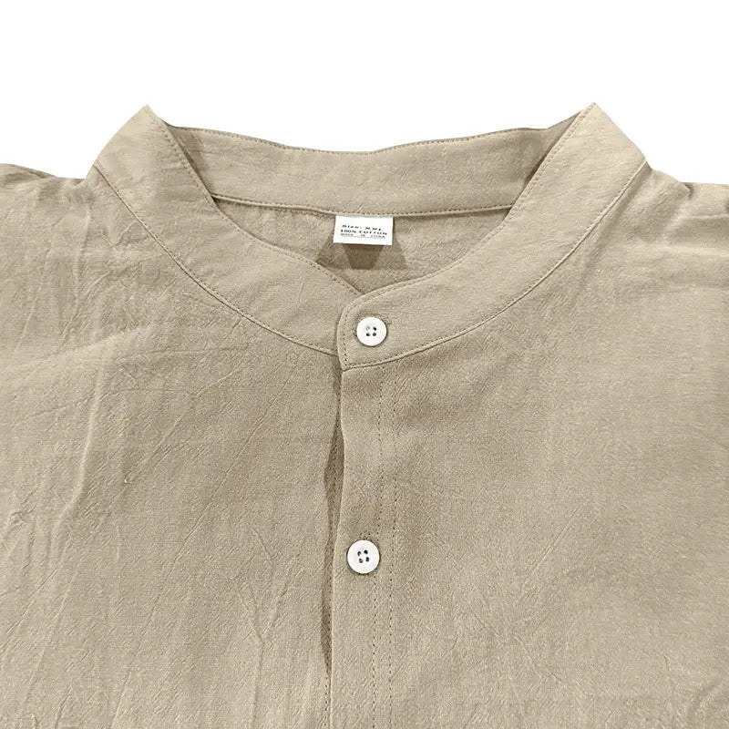 Beiges Leinenhemd für Herren mit Stehkragen und weißen Knöpfen als Teil eines Sets aus Leinenhemd und -hose.