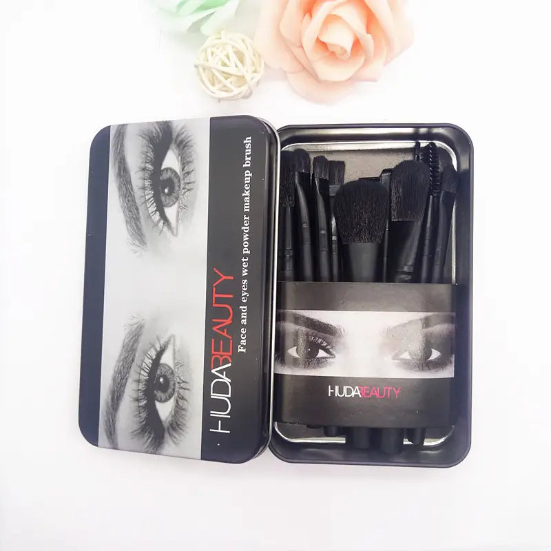 Ensemble de pinceaux de maquillage pour visage et yeux à poudre humide Huda Beauty noir, 12 pièces professionnelles, dans un étui rectangulaire, présentant une imagerie monochrome des yeux.