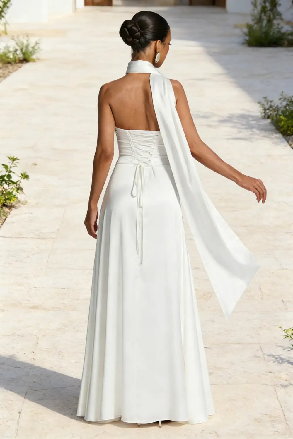 Un vestido de noche de satén blanco, fluido y sin tirantes, con escote alto, cordones del corsé en la espalda y una manga drapeada asimétrica diseñada para ocasiones formales elegantes