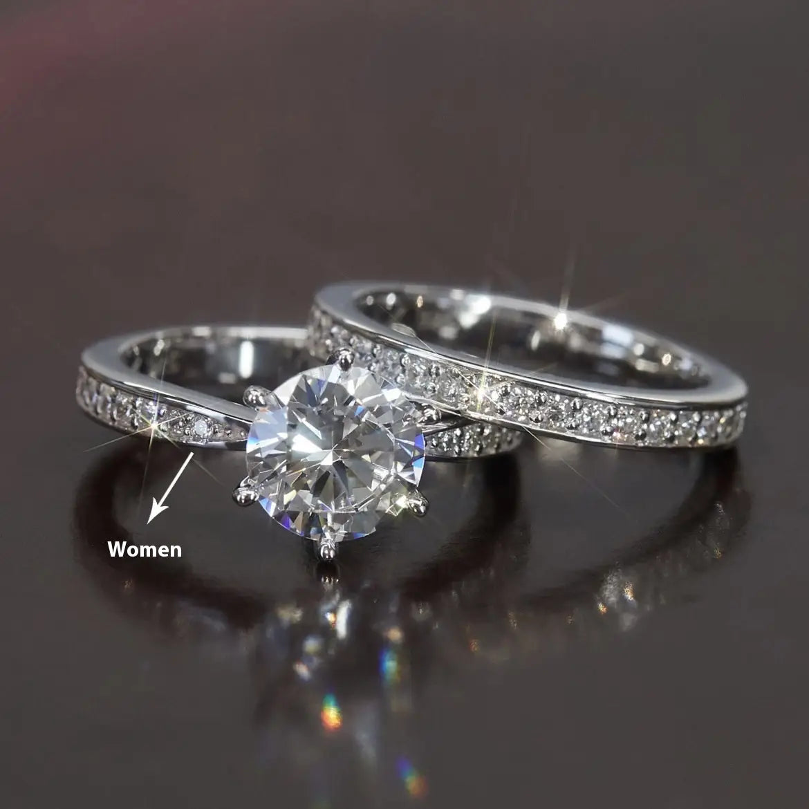 A sparkling white gold finish round cut zircon wedding ring set featuring a central round cut stone with a pave set band paired with an eternity wedding band.