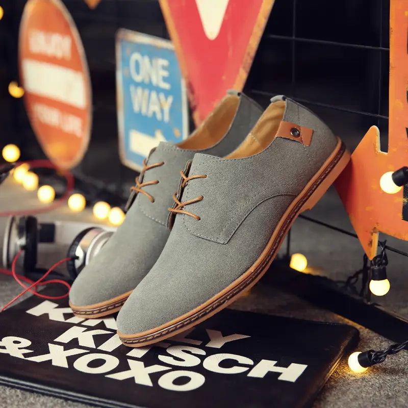 Graue Wildleder-Oxford-Schuhe für Herren mit beigen Schnürsenkeln und braunen Lederakzenten, mit Schnürdesign und Leder-Flats.