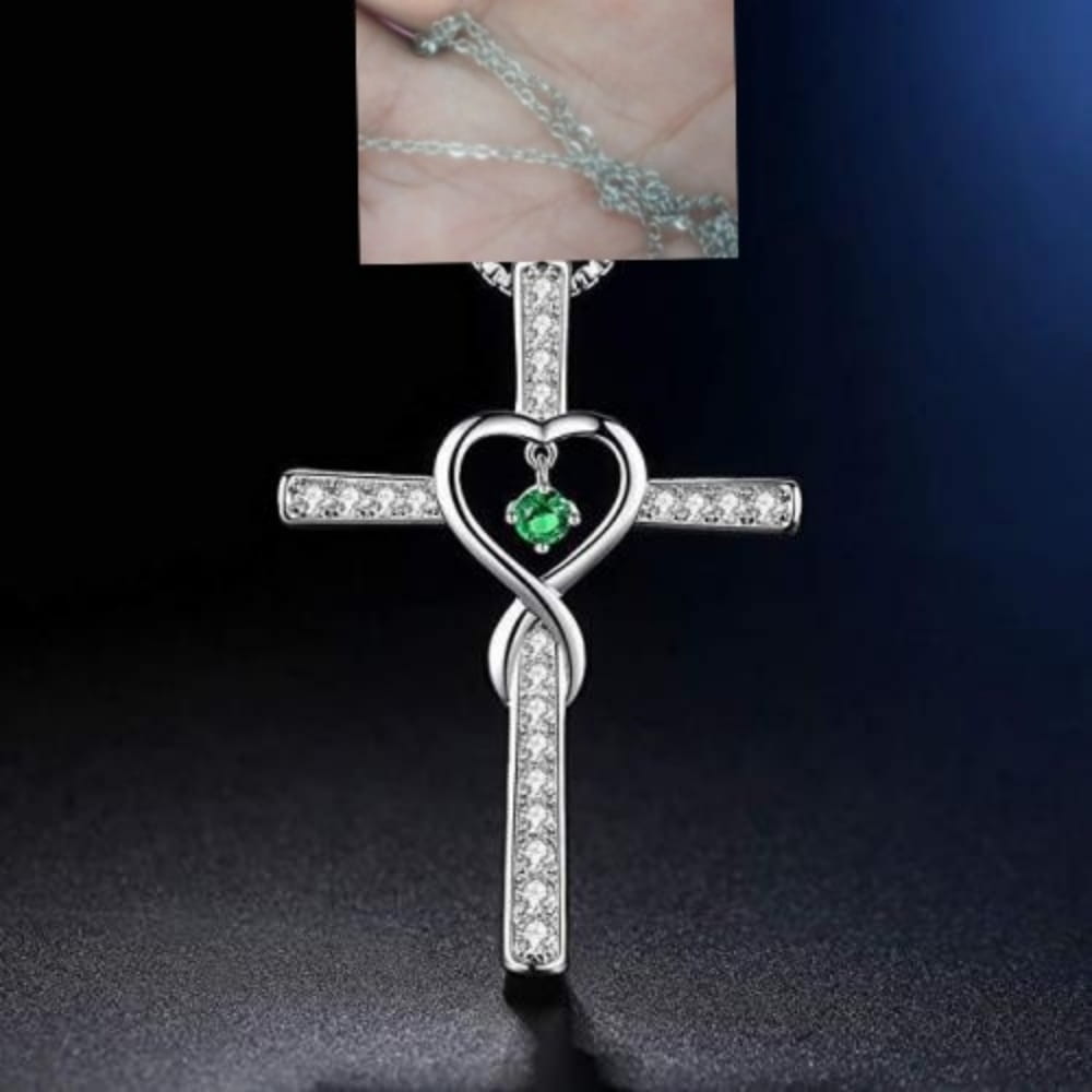 Silver cross pendant necklace named infinity love heart cross birthstone crystal necklace featuring a heart-shaped center with a green gemstone and clear crystals along its arms.