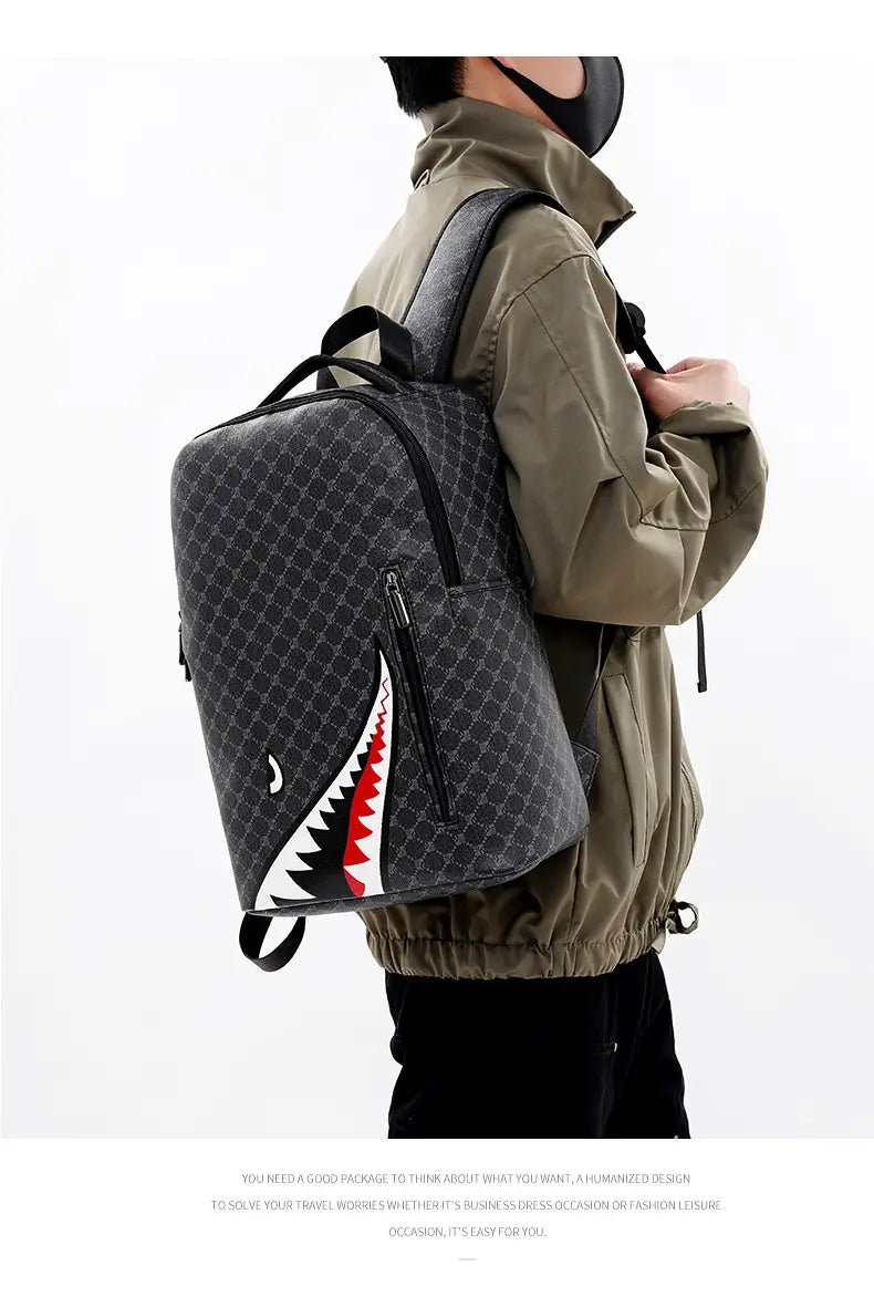 Black backpack with bold shark mouth design in red and white accents on a textured gray pattern, made of PU material, large capacity for business use.