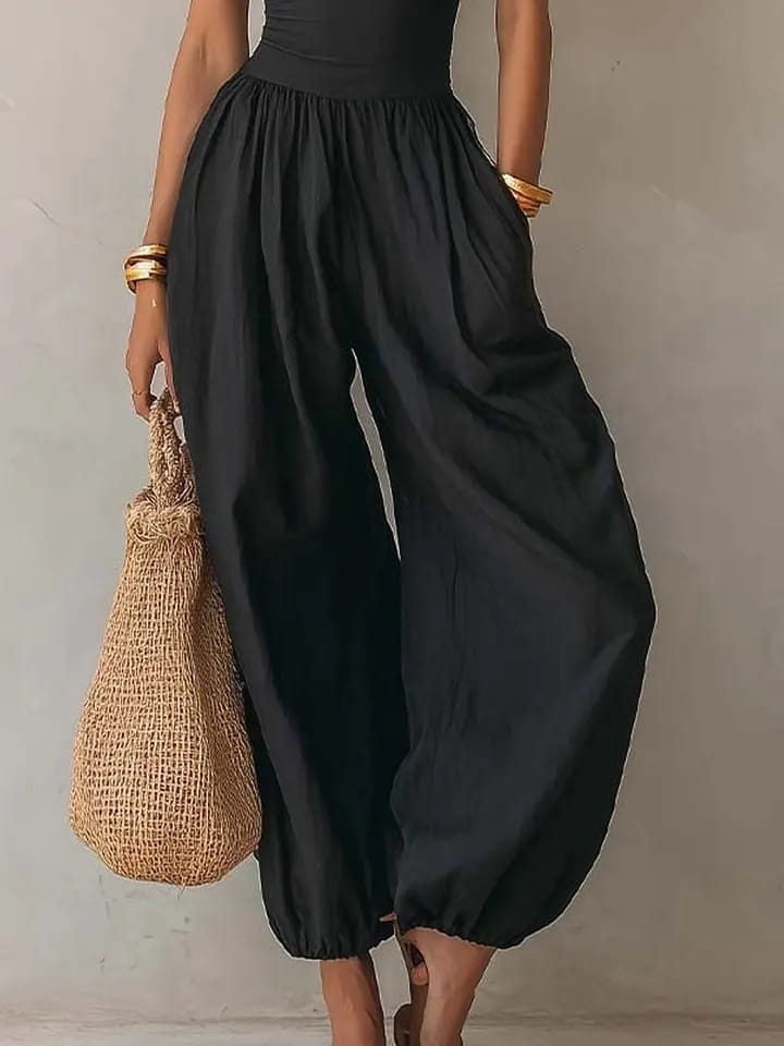 Mono tipo halter de pierna ancha en color negro con pantalones de tiro alto y pierna ancha en color negro, con caída suelta y fluida, y puños elásticos.