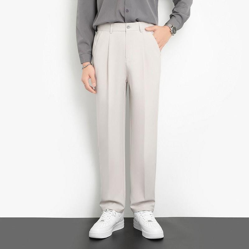 Men loose fit straight leg suit pants in beige featuring a sleek modern cut and subtle textured pleated design.