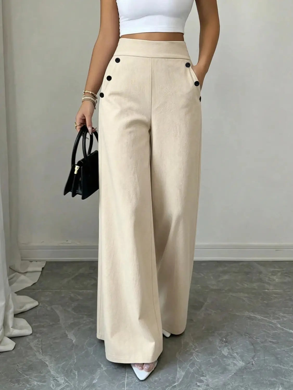 Pantalon ample taille haute beige avec accents de boutons noirs, confectionné dans une matière souple pour un rendu élégant et confortable