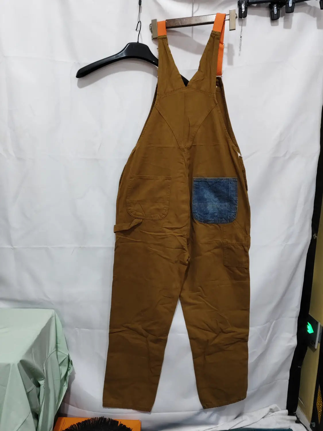 men cargo suspender jumpsuit in brown denim featuring a blue patch pocket and orange shoulder straps