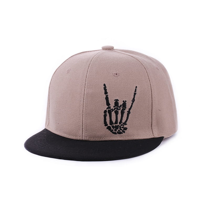 Beige and black snapback baseball cap featuring a black embroidered skeleton hand gesture on the front panel.