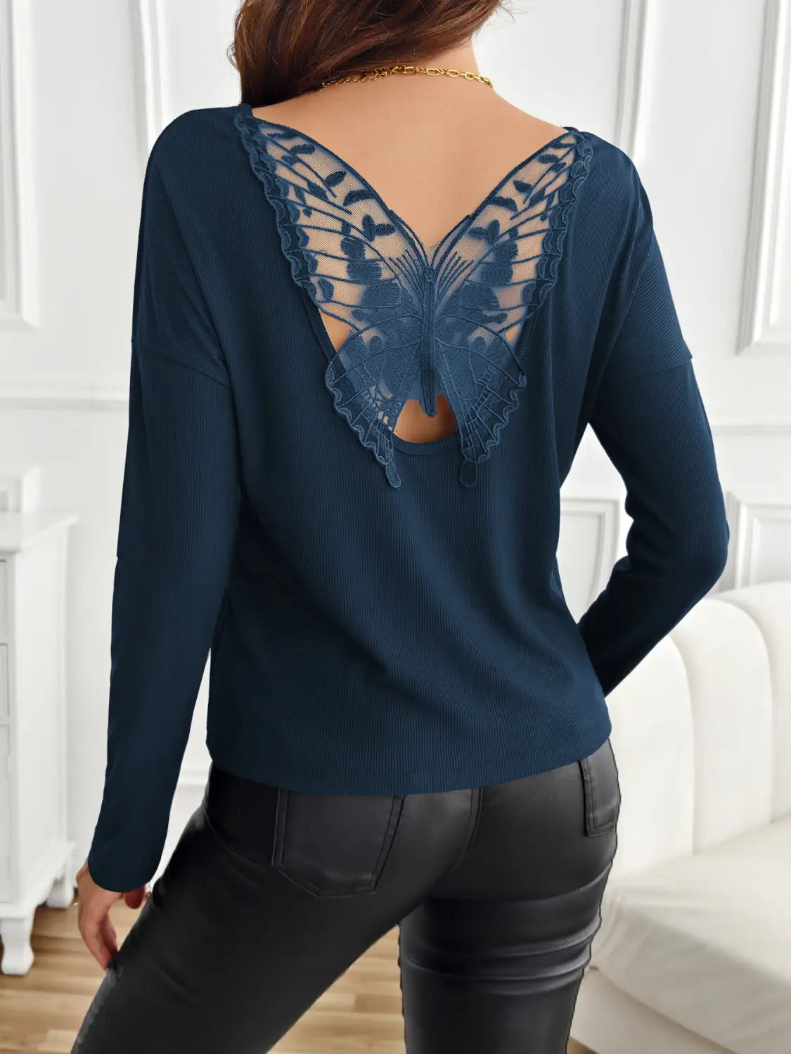 dark blue long-sleeved ribbed knit top with an intricate butterfly-shaped lace detail on the back side.