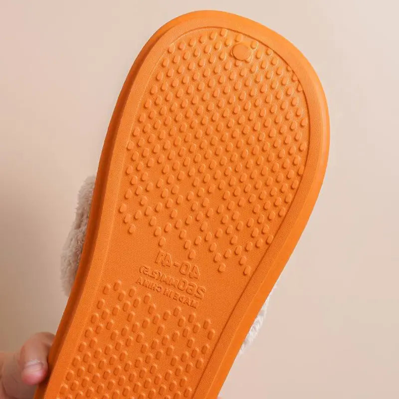 orange rubber sole with textured grip pattern and embossed brand markings on the back side of washable plush house shoes for women winter slippers