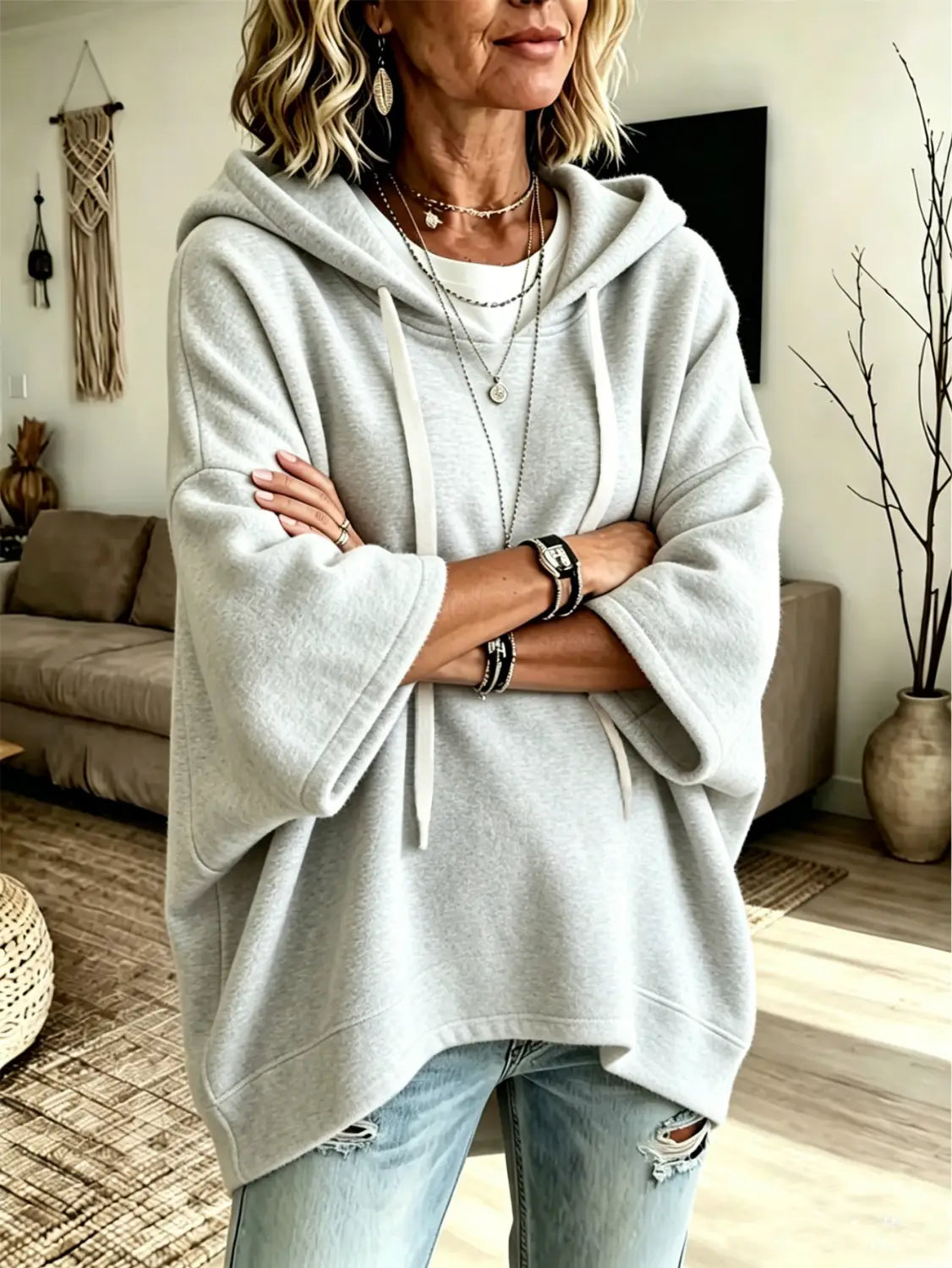 Light gray oversized fleece hooded top with a soft loose fit, three-quarter sleeves, and matching drawstrings.