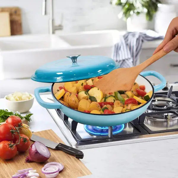A vibrant turquoise enameled cast iron braiser 3.8 qt casserole pot with matching lid and two sturdy handles filled with colorful roasted vegetables.