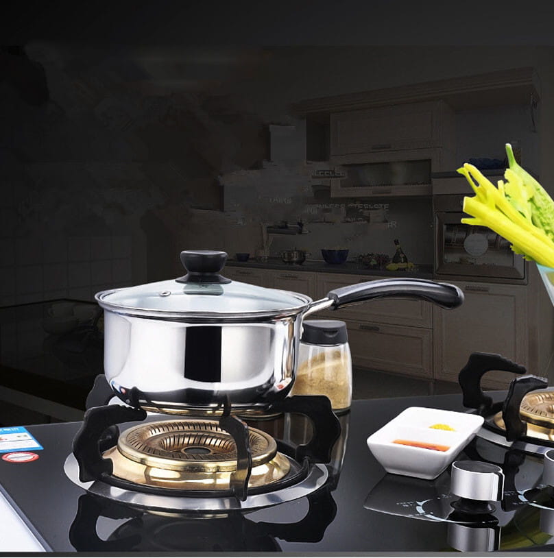 Cazo/cacerola de acero inoxidable brillante con asa negra y pomo de la tapa sobre el quemador de una cocina eléctrica de un juego de utensilios de cocina de acero inoxidable para inducción con tapas de vidrio.
