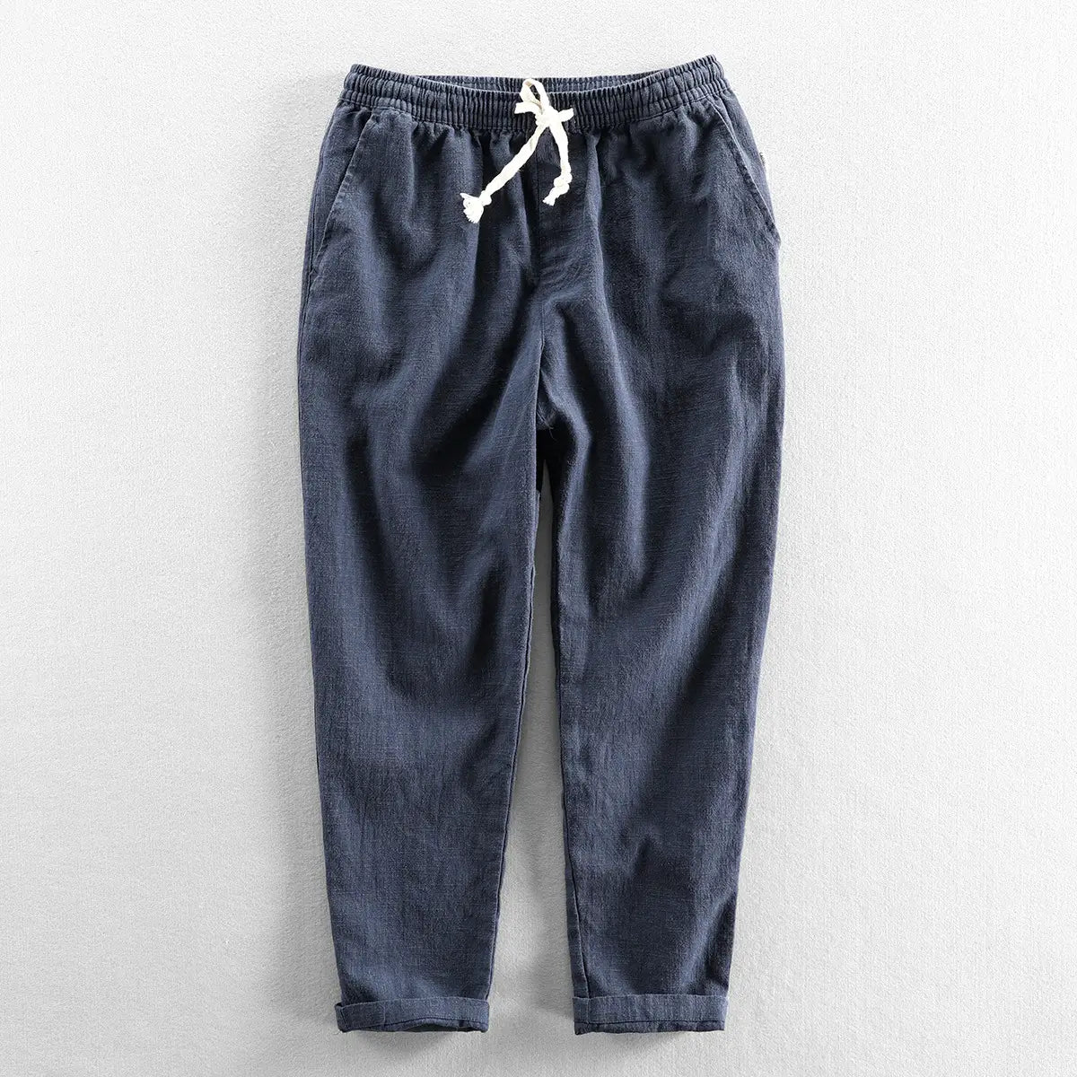 Men’s relaxed fit linen joggers in dark blue corduroy with a white drawstring waistband and rolled cuffs.