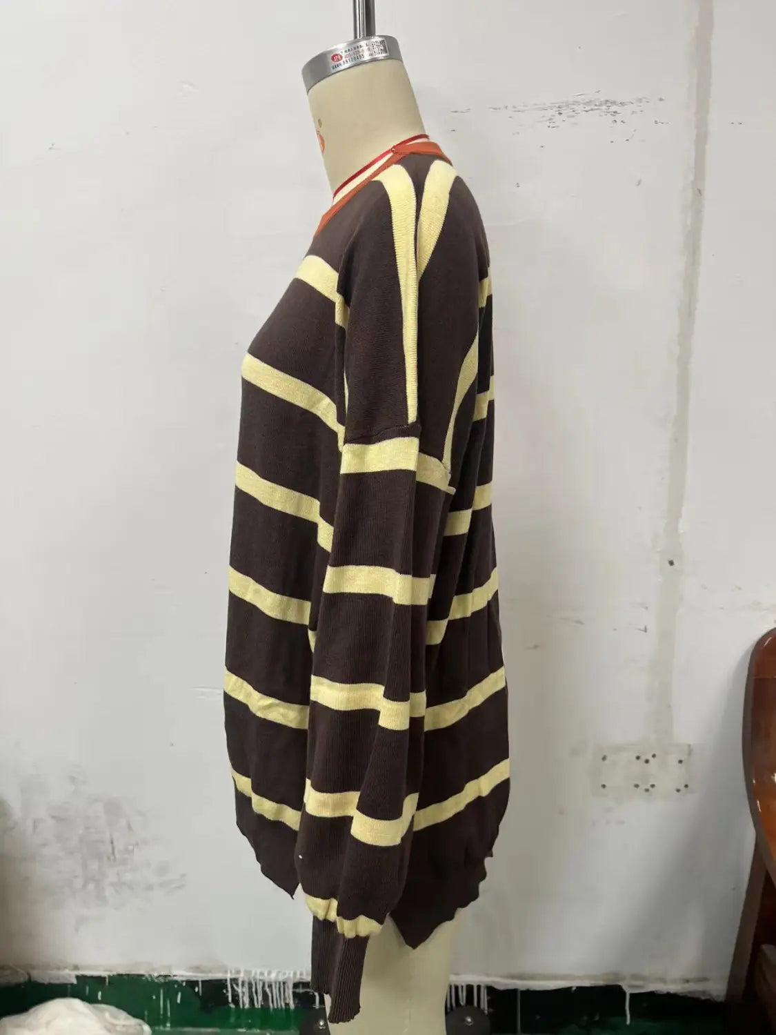 A brown and cream striped oversized knit sweater for women featuring long sleeves and ribbed neckline cuffs and hem.