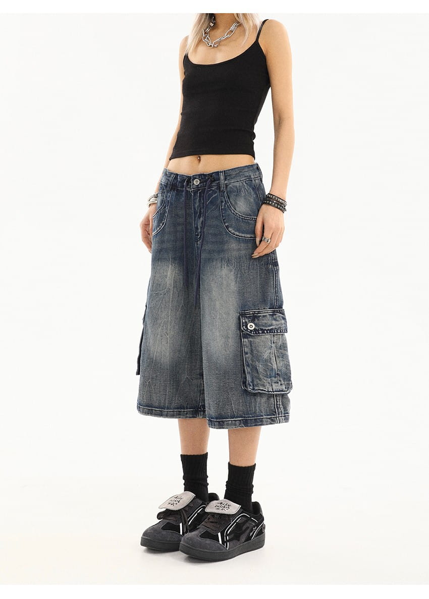 Falda cargo de mezclilla azul en mezclilla oscura con múltiples bolsillos y un aspecto ligeramente descolorido y envejecido para estilo urbano.