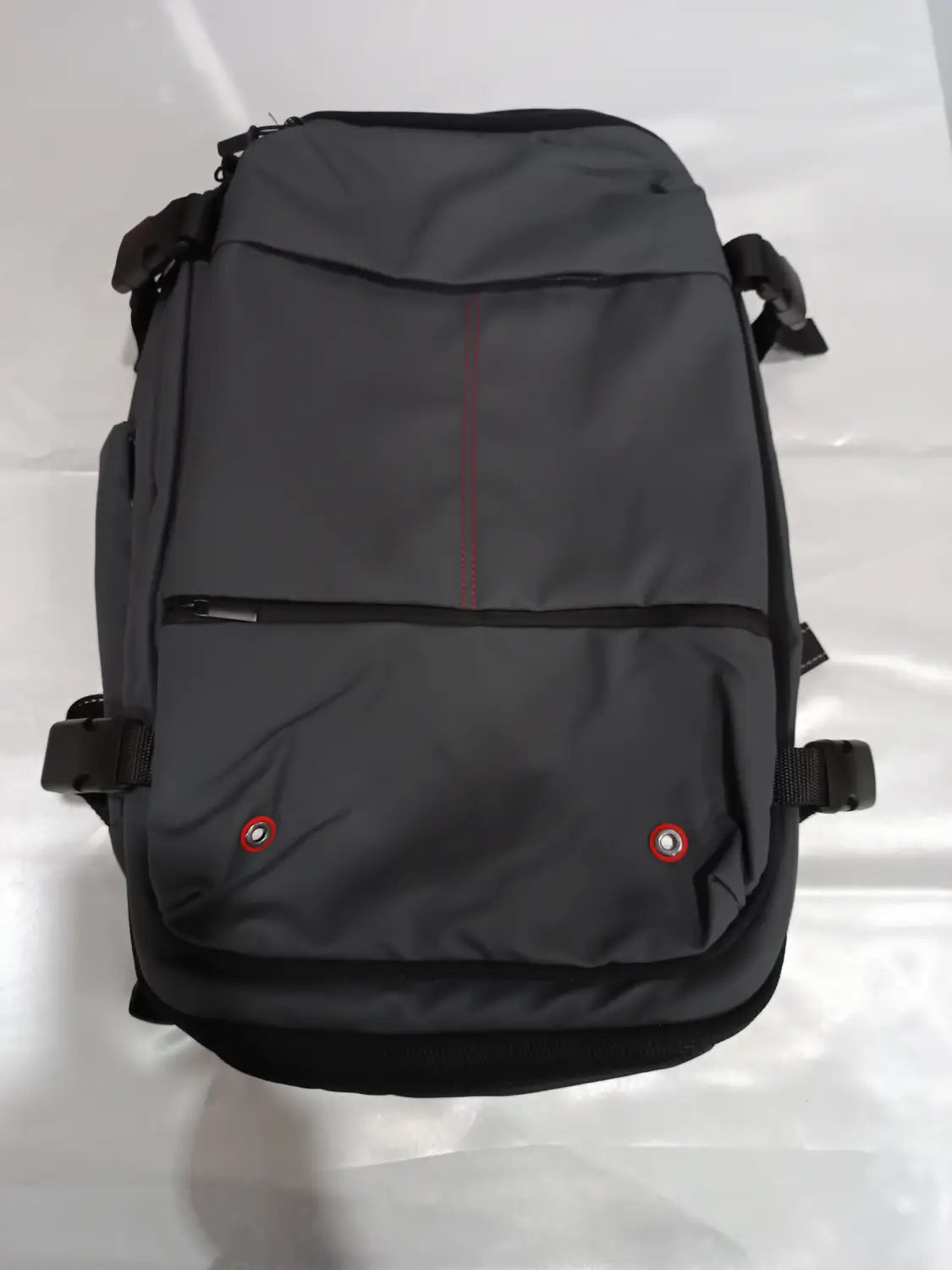 Dark gray nylon travel backpack with black trim and red accent stitching designed as a vacuum compression business laptop bag.
