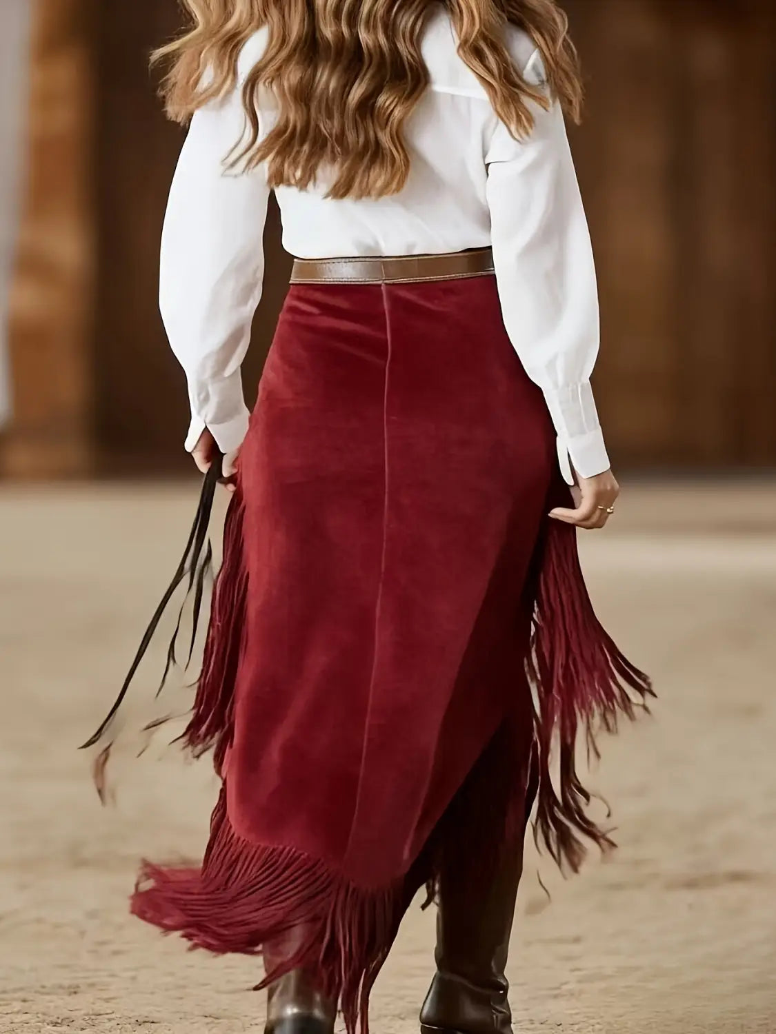 Ein edler bordeauxroter Samtrock mit langen, fließenden Fransenverzierungen in einem asymmetrischen Western-Design.