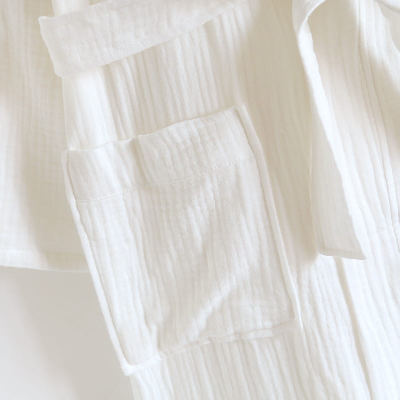 Peignoir en gaze de coton blanc pour homme présentant un tissage texturé souple et une poche cousue avec soin.
