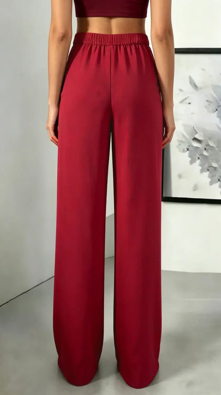 Pantalons plissés rouges à taille haute et jambes larges avec une ceinture élastique, adaptés à une tenue stylée et confortable.