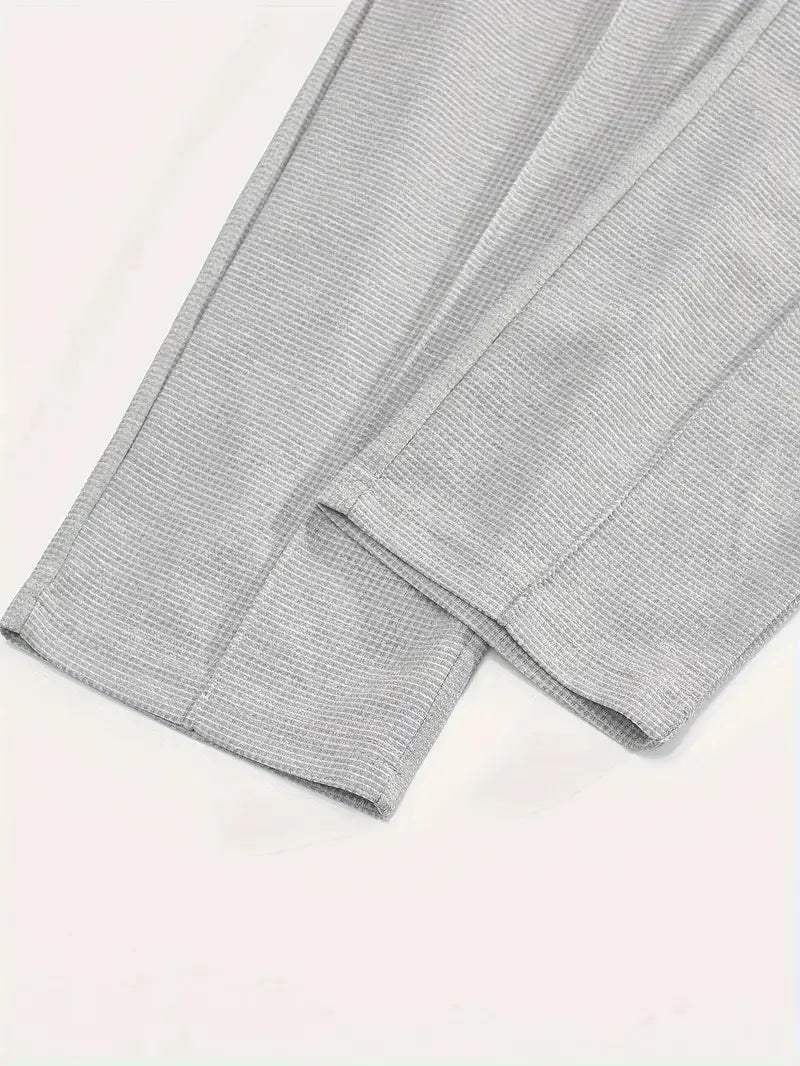 Gray textured knit pants with a subtle ribbed pattern and neatly folded cuffs from the mens minimalist solid color sweatshirt jogger set.