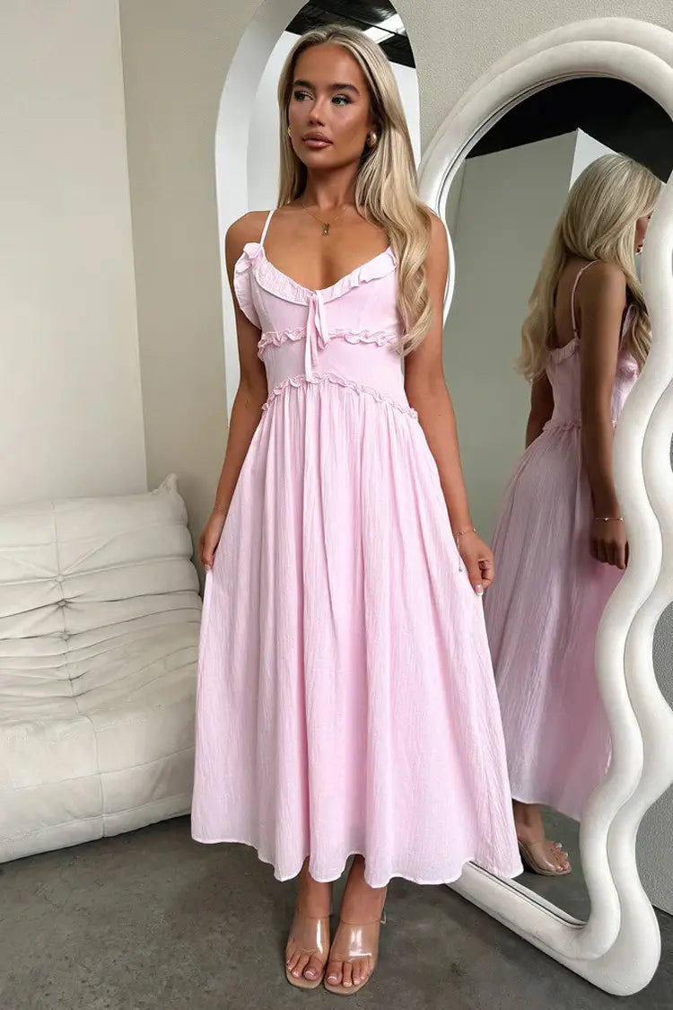 A soft pink flowing maxi vacation dress featuring delicate ruffled straps and a gathered waist.