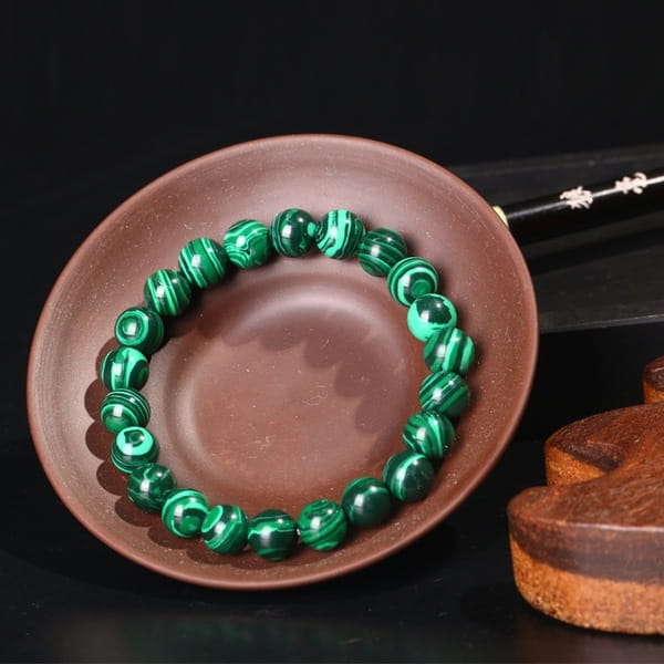 A matte black and green malachite elastic bead bracelet featuring polished green beads with swirling black patterns and smooth round shapes.