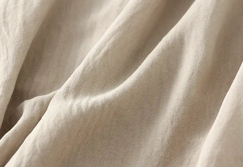 Beige linen pleated wide flare maxi skirt with a soft textured weave and gentle folds.