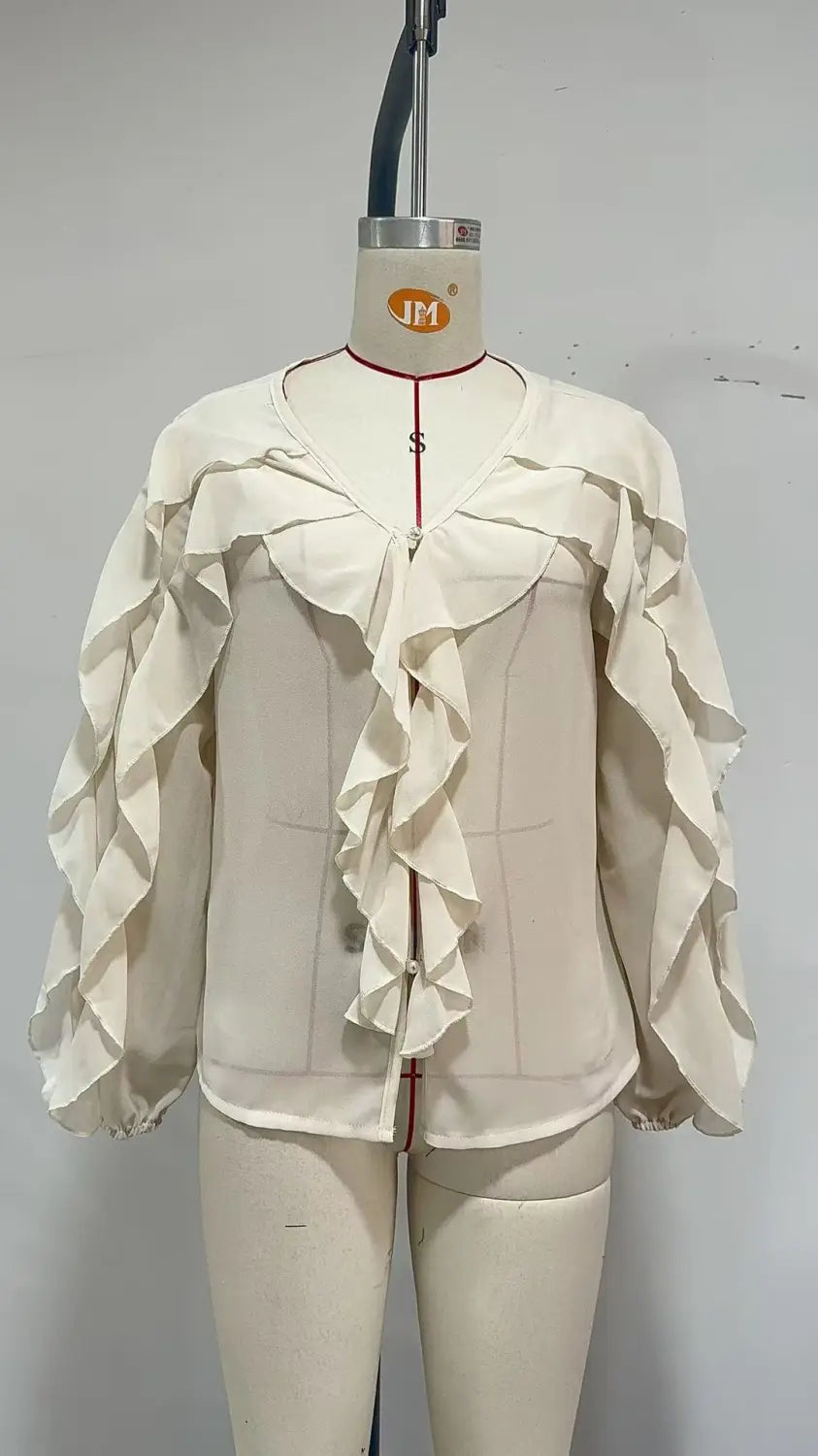Wollweiße Volant-Chiffonbluse mit mehrlagigen Rüschen und tailliertem Oberteil als lässiges Oberteil mit langen Ärmeln, auf einem Schaufensterfigürchen präsentiert.