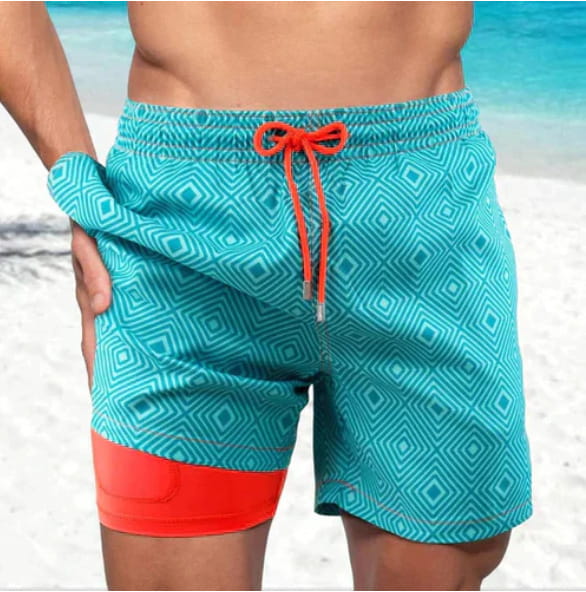 Men’s geometric print double layer beach shorts in teal with a geometric pattern and orange drawstring and hem.