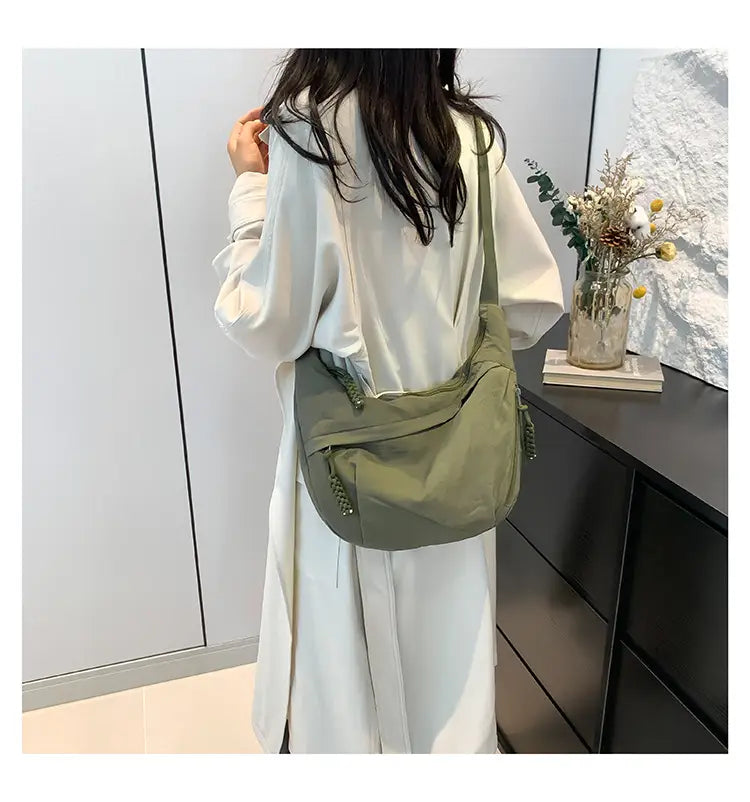 Olive green nylon crossbody bag with braided tassel details designed as a large capacity hobo shoulder bag.