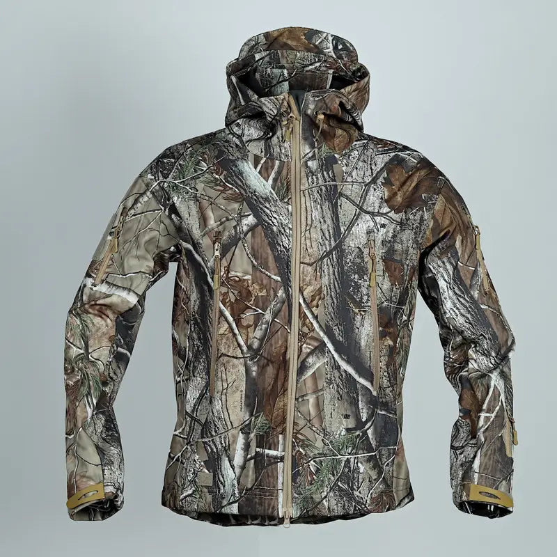Veste tactique softshell à capuche avec motif camouflage dans des tons brun, gris et vert, conçue pour imiter le feuillage de la forêt.