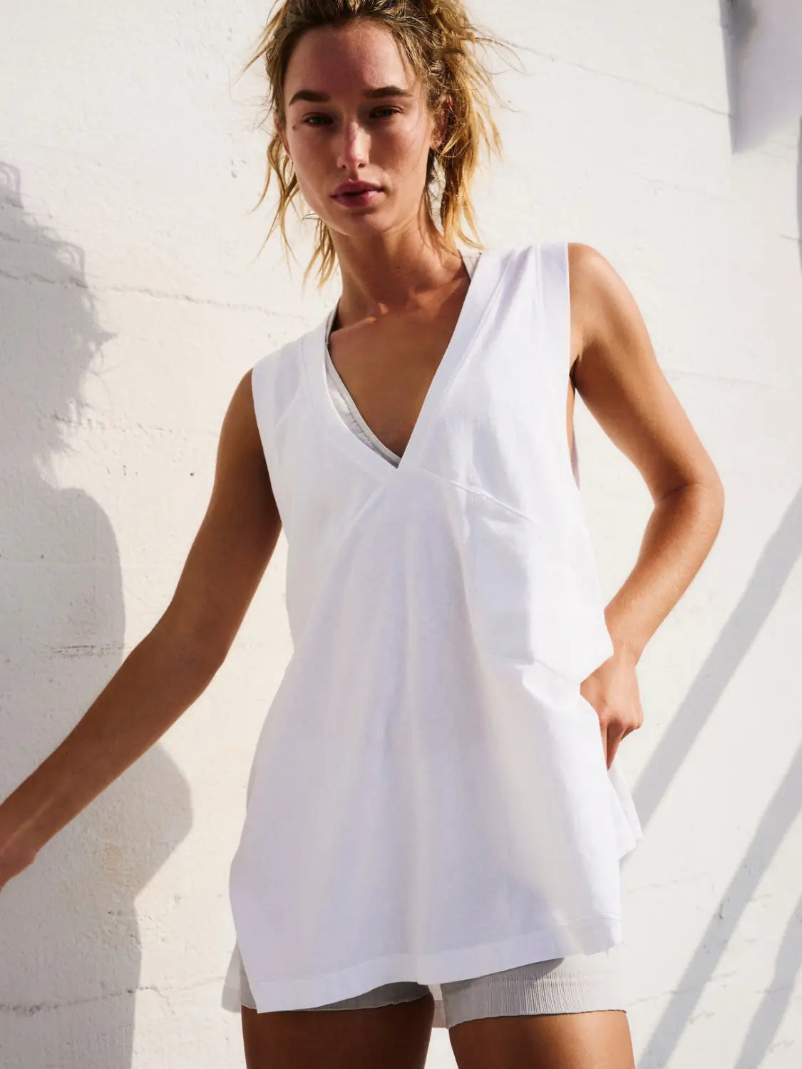 White sleeveless cotton vest top with a relaxed flowing silhouette and v neck wrap design.