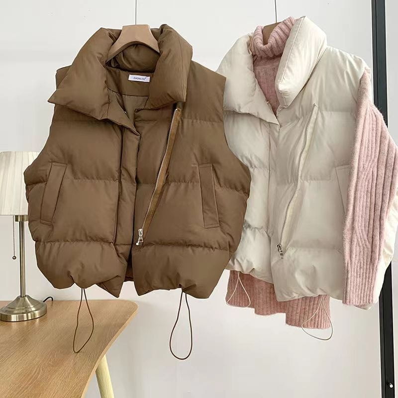 Brown quilted sleeveless puffer vest for women with a high collar, front zipper, two side pockets, and drawstrings at the hem.