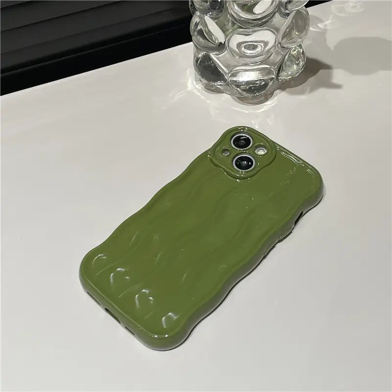 Olive green glossy wavy liquid silicone iPhone case showing the back side with a textured surface and precise camera cutouts.