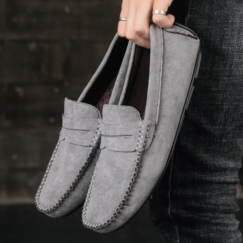 Mocassins en daim gris cousus à la main, présentant un détail de chaîne cousue le long de l’avant-pied, issus de la collection de chaussures en velours confectionnées à la main.