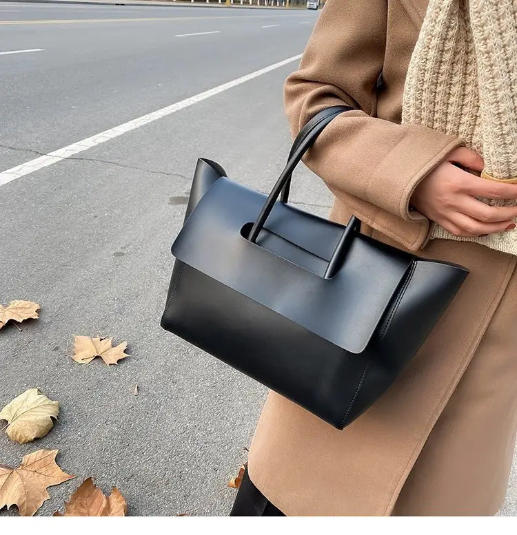 Black leather tote bag with a vintage structured minimalist design and sleek top handles.