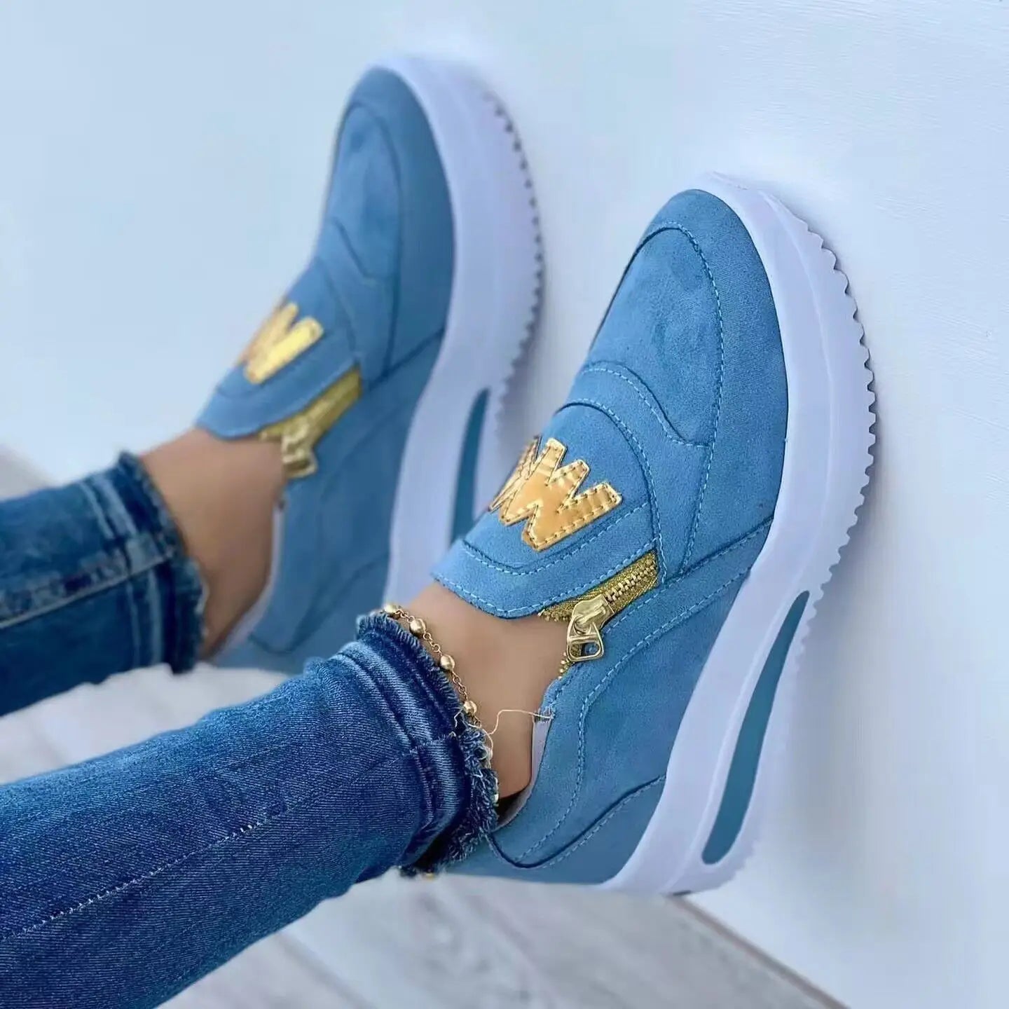 Baskets compensées à enfiler pour femmes en daim bleu clair, ornées d’accents de fermeture éclair ton sur ton doré et d’une semelle plateforme blanche.