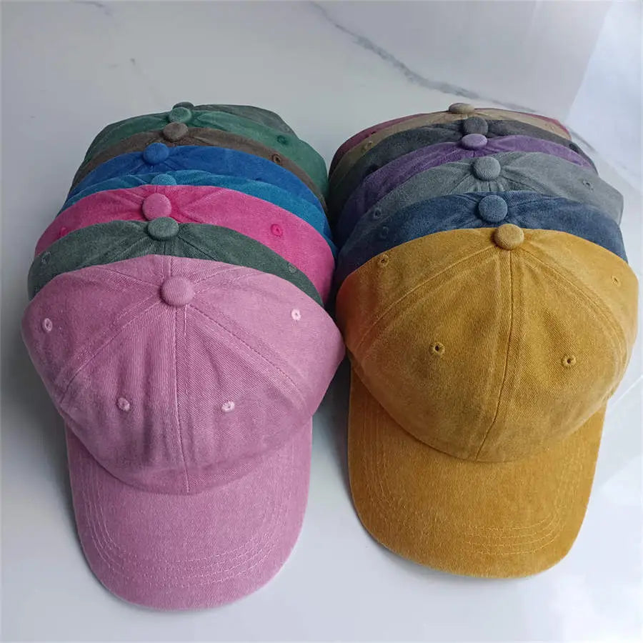 A collection of colorful soft-textured cotton baseball caps in pastel and earthy tones with matching button accents on the crown showcasing vintage washed sun hat style.