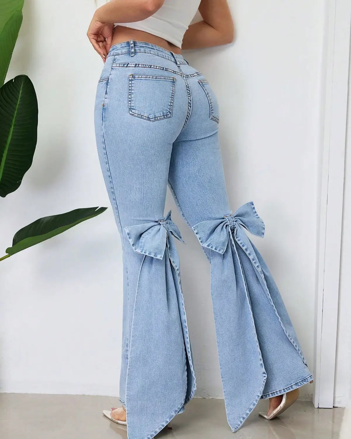Jean évasé taille haute en denim délavé clair avec des nœuds décoratifs aux genoux en denim bleu clair.
