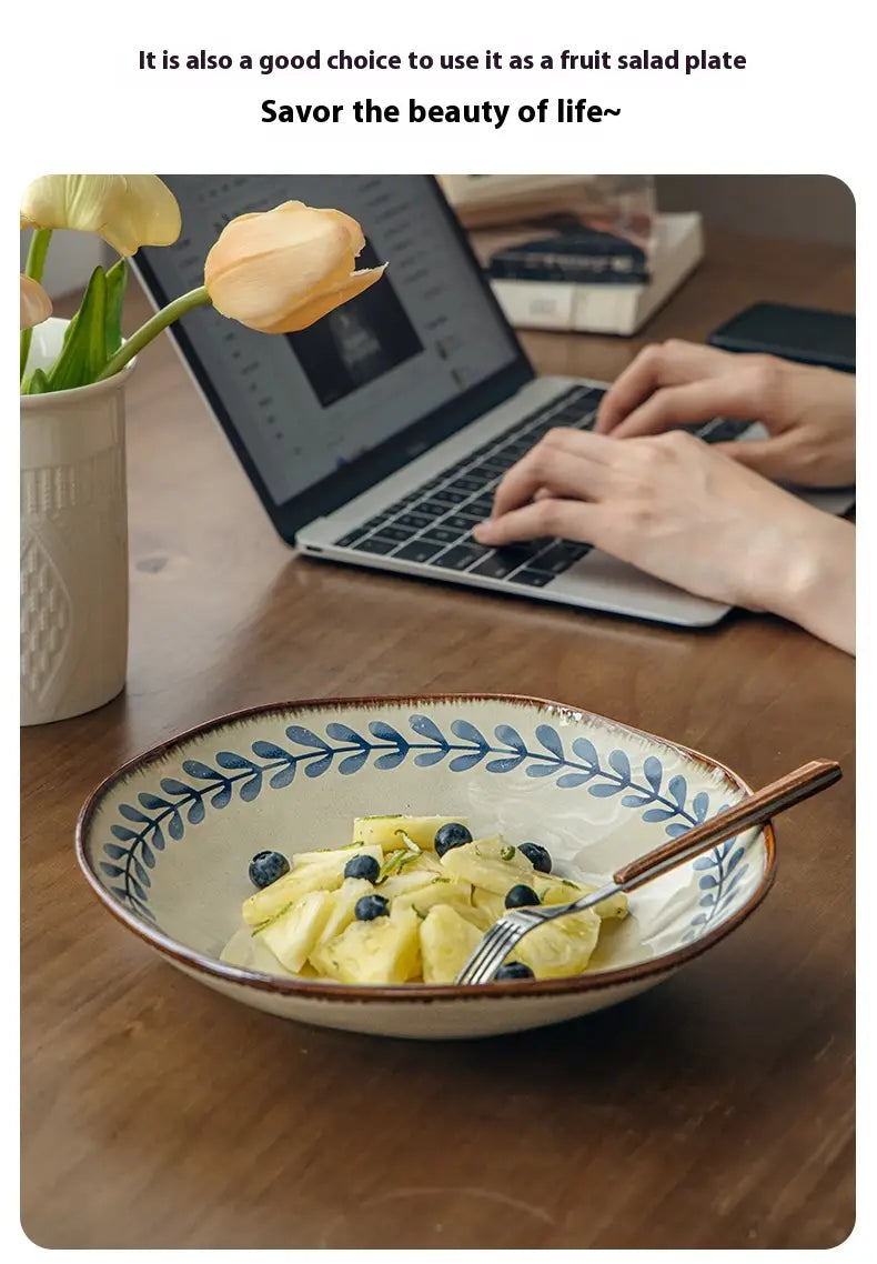 Cream-colored 9-inch ceramic deep plate with brown rim and blue leaf pattern filled with pineapple chunks and blueberries.