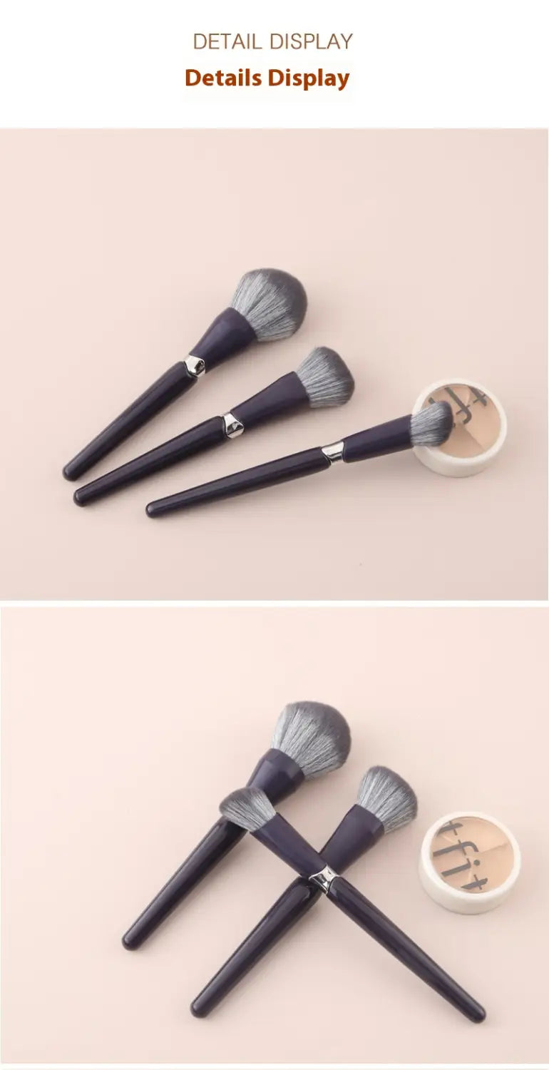 set of three dark purple makeup brushes with soft gray bristles and silver accents displayed with a white circular brush holder for face powder application