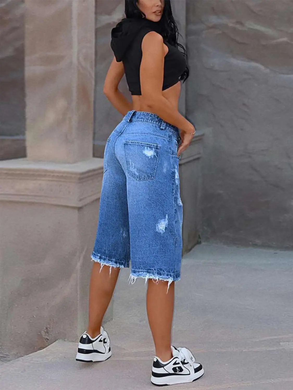 Pantalones capri de mezclilla azul con desgarros y efecto desgastado, con dobladillos deshilachados, elaborados con material de mezclilla resistente.