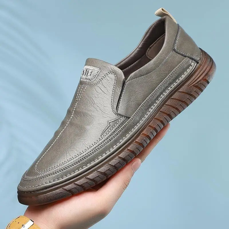 Men’s breathable non slip gray leather slip-on loafers with textured sole and visible stitching.