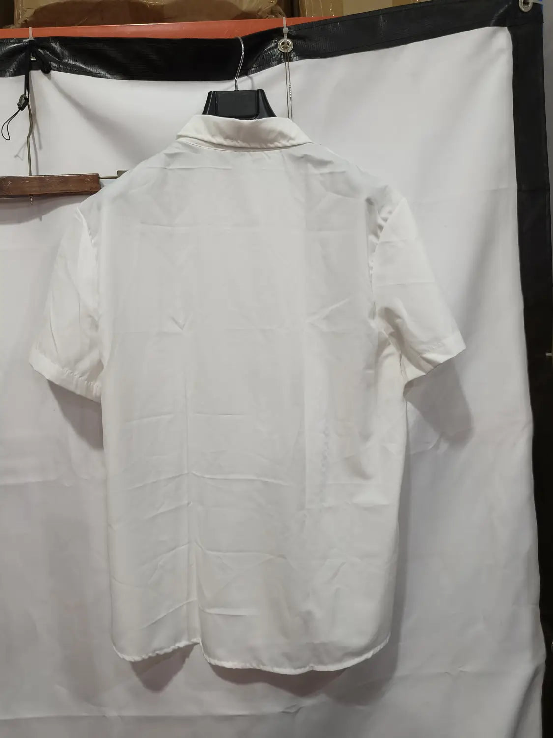 Ein crispes weißes Herren-Leinenhemd mit Knopfleiste, Kurzarm, leger, mit klassischem Kragen und ordentlich eingefassten Ärmeln.
