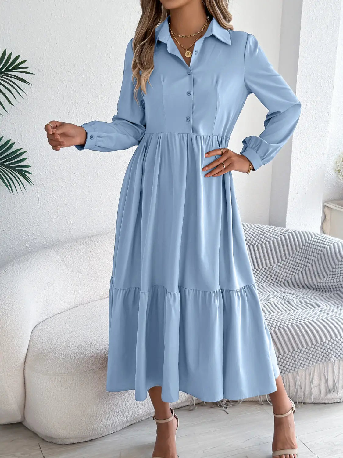 A light blue women’s long sleeve tiered button down midi dress with a collar and a flowing skirt made from soft fabric.