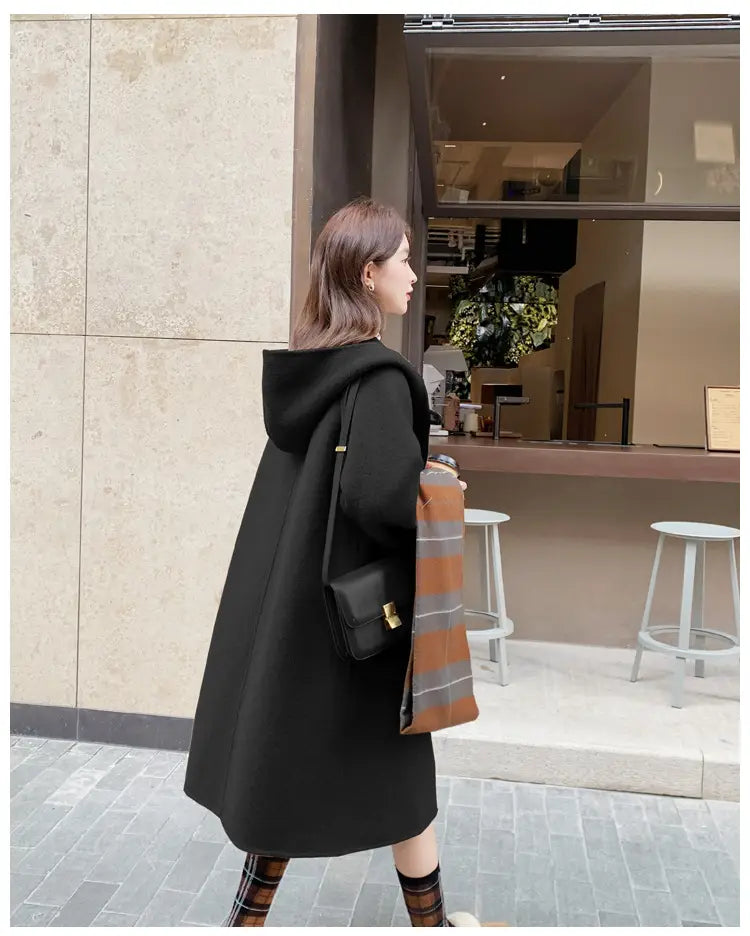 Schwarzer Wollmantel mit Kapuze, Winter-Outdoorbekleidung mittlerer Länge, mit einem eleganten modernen Design und weicher Stoffstruktur, von der Rückseite gezeigt.