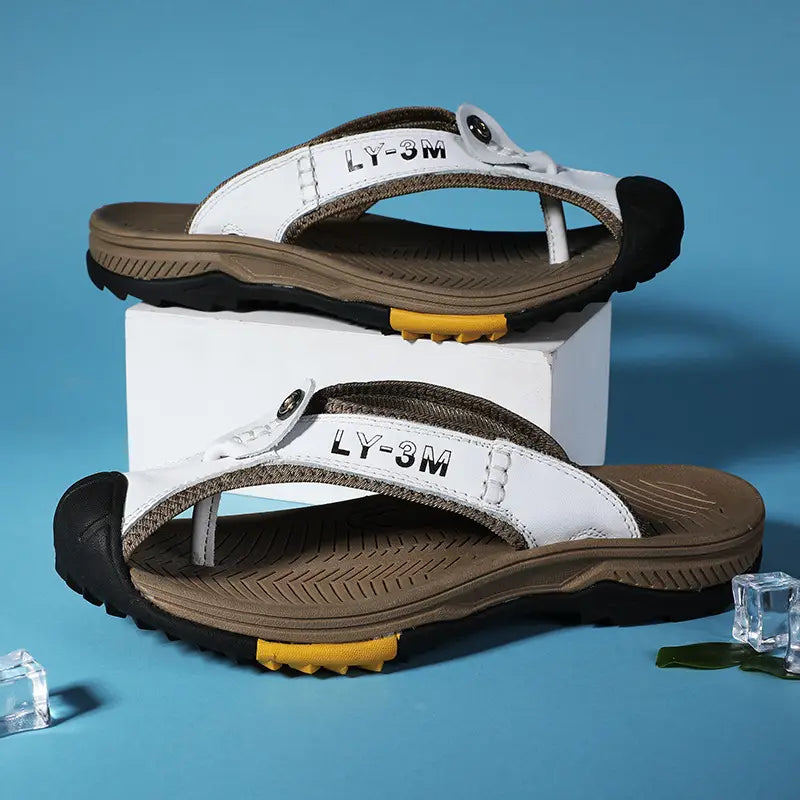 Men’s leather beach sandals outdoor sport flip flops in white and brown with textured sole black rubber toe caps and yellow accents on the heel shown from the back side.